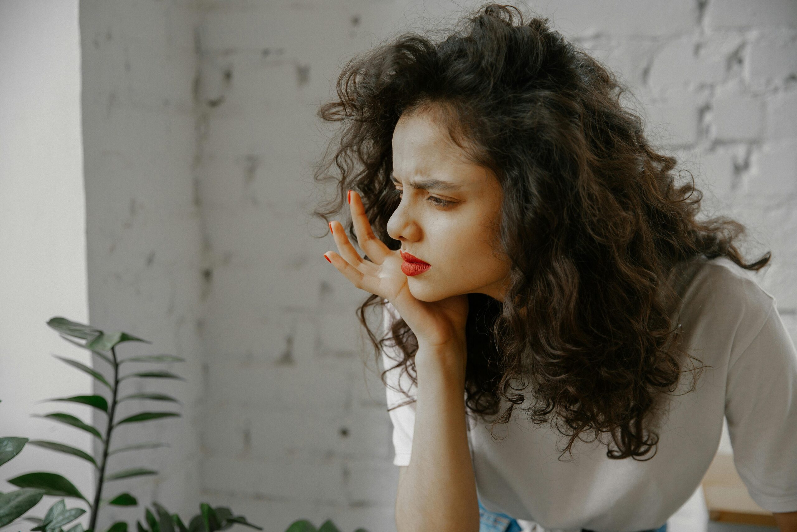 Image of a woman looking tired and disheveled, sitting up as if she just woke up, illustrating the concept of hangover vs. alcohol withdrawal and the physical effects of drinking.