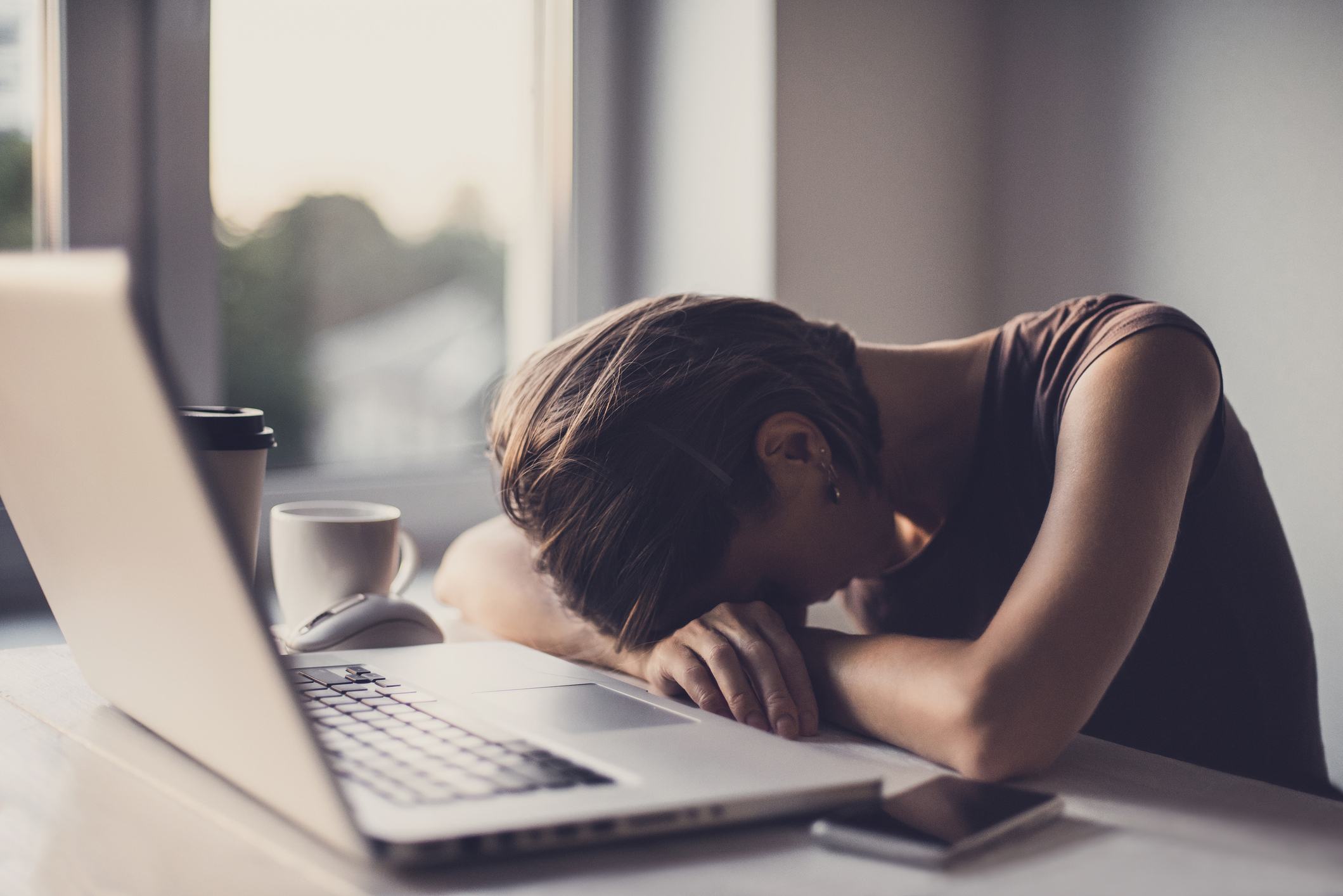 A woman with her head down at an office desk, appearing overwhelmed, symbolizing the challenges of using Xanax for alcohol withdrawal.